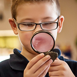 boy looking through magnifying glass with glasses