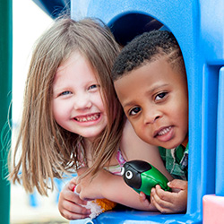 kids smiling in window of play house